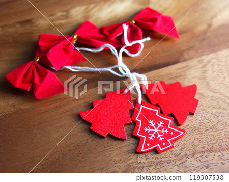 New Year and Christmas toys: red bows and wooden Christmas trees on a wooden board background. Holiday decor, religion and culture New Year and Christmas toys: red bows and wooden Christmas trees on a wooden board background. Holiday decor, religion and culture 119307538