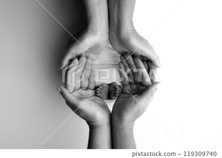 The palms of the parents. A father and mother hold the feet of a newborn child in a blanket. The feet of a newborn in the hands of parents. Black and white Photo of foot, heels and toes The palms of the parents. A father and mother hold the feet of a newborn child in a blanket. The feet of a newborn in the hands of parents. Black and white Photo of foot, heels and toes 119309740
