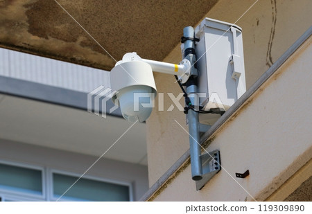 Remote-controlled surveillance camera installed on the wall of a building Remote-controlled surveillance camera installed on the wall of a building 119309890