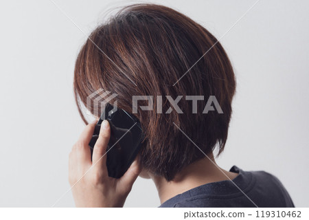 Back view of a middle-aged woman talking on a smartphone Back view of a middle-aged woman talking on a smartphone 119310462