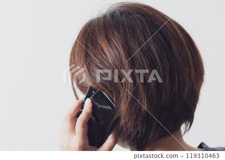 Back view of a middle-aged woman talking on a smartphone Back view of a middle-aged woman talking on a smartphone 119310463