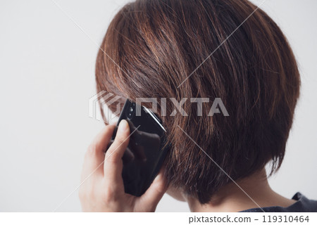 Back view of a middle-aged woman talking on a smartphone Back view of a middle-aged woman talking on a smartphone 119310464