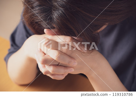 Middle-aged woman looking down with hands folded 119310786