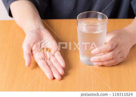 Hands of a middle-aged woman taking supplements Hands of a middle-aged woman taking supplements 119311024