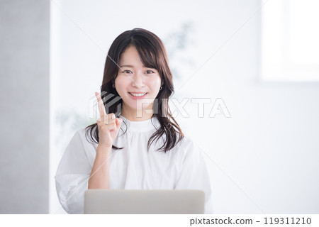A woman sitting at a desk with a computer and posing with recommendations and points, looking at the camera A woman sitting at a desk with a computer and posing with recommendations and points, looking at the camera 119311210