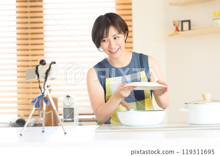 A woman recording a cooking video in the kitchen A woman recording a cooking video in the kitchen 119311695