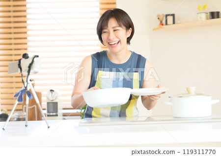 A woman recording a cooking video in the kitchen A woman recording a cooking video in the kitchen 119311770