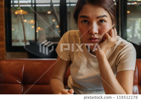 Woman working online with computer tablet in a cafe, looking at the camera 119312178