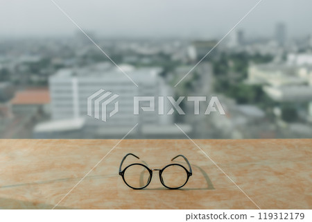 Eyeglasses on wooden desk with city view. 119312179
