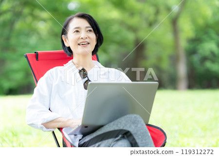 A middle-aged woman working remotely at a campsite 119312272