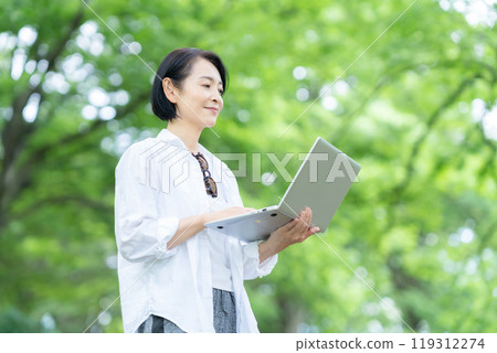 A middle-aged woman working remotely at a campsite A middle-aged woman working remotely at a campsite 119312274