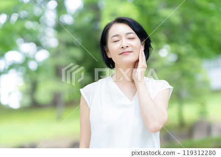 一位中年婦女在新綠中做皮膚護理 119312280