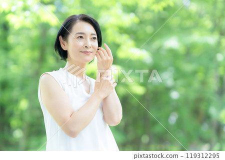 一位中年婦女在新綠中做皮膚護理 119312295