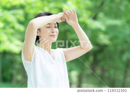 一位中年婦女在新綠中做皮膚護理 119312301