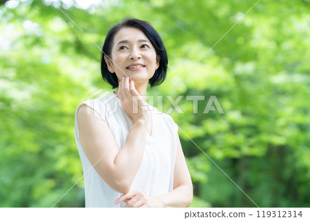 一位中年婦女在新綠中做皮膚護理 119312314