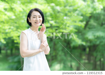 一位中年婦女在新綠中做皮膚護理 119312315