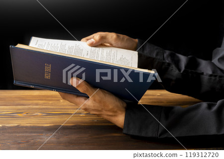 Man reading a holy bible in his hand. Symbol of faith and worship in God. People christianity prayer in church 119312720