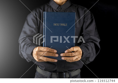 Man holding a holy bible in his hand. Symbol of faith and worship in God. People christianity prayer in church 119312744