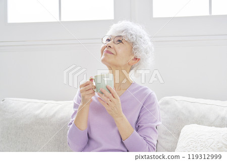 Portrait of a senior woman relaxing in living room Portrait of a senior woman relaxing in living room 119312999