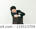 20 多歲的日本男子穿著西裝坐在椅子上，看著他的智慧型手機 119313709