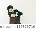20 多歲的日本男子穿著西裝坐在椅子上，看著他的智慧型手機 119313710