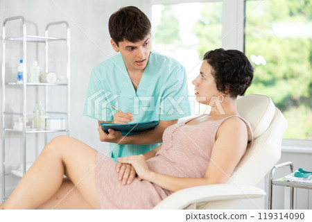 Doctor cosmetologist writes down the complaints of female patient in cosmetology clinic 119314090