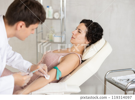Male anesthesiologist injecting anesthetic into vein on her arm with syringe in cosmetology clinic Male anesthesiologist injecting anesthetic into vein on her arm with syringe in cosmetology clinic 119314097