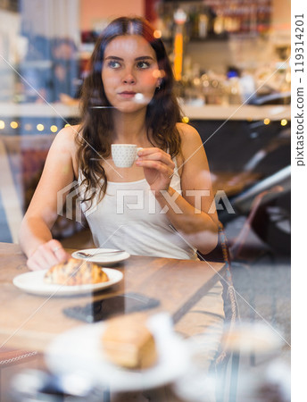 Portrait of young woman drinking coffee in cafe Portrait of young woman drinking coffee in cafe 119314201