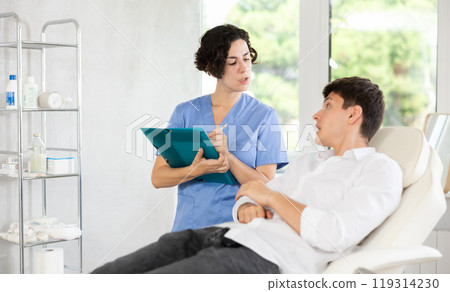 Female doctor communicates with male patients in cosmetology clinic before surgery 119314230