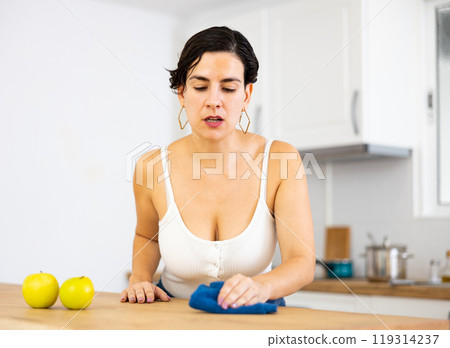 Young Chilean woman wiping dust from kitchen table 119314237