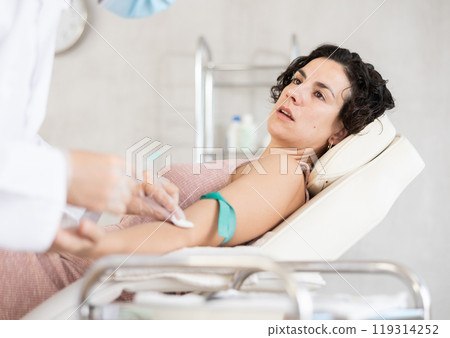 Male anesthesiologist injecting anesthetic into vein on her arm with syringe in cosmetology clinic Male anesthesiologist injecting anesthetic into vein on her arm with syringe in cosmetology clinic 119314252