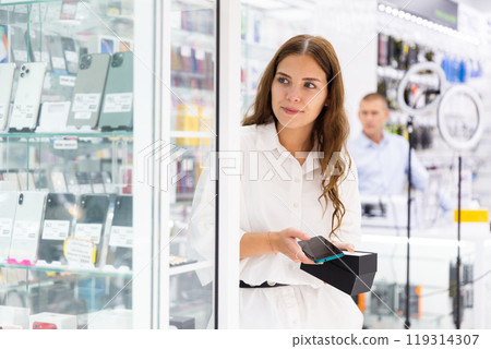 Young woman choosing phone in consumer electronics store Young woman choosing phone in consumer electronics store 119314307
