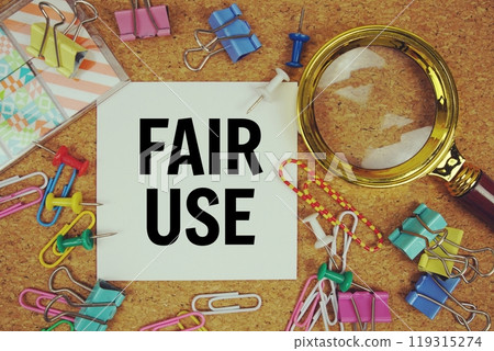 Fair Use text on paper card with magnifying glass and stationery on cork board background Fair Use text on paper card with magnifying glass and stationery on cork board background 119315274