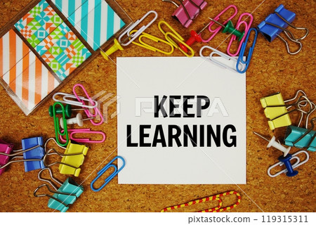 Keep Learning text on paper card with stationery on cork board background 119315311