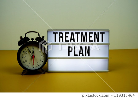 Treatment Plan text on LED lightbox with alarm clock on yellow background 119315464