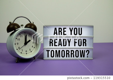 Are you ready for tomorrow? text on LED lightbox with alarm clock on purple background Are you ready for tomorrow? text on LED lightbox with alarm clock on purple background 119315510