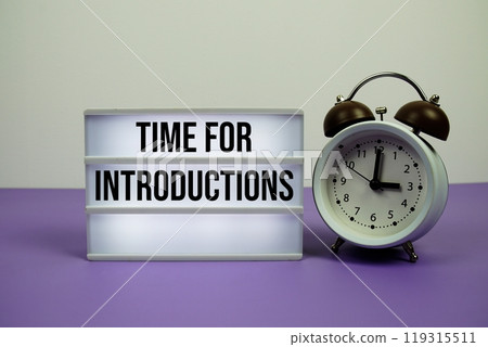 Time For Introductions text on LED lightbox with alarm clock on purple background Time For Introductions text on LED lightbox with alarm clock on purple background 119315511