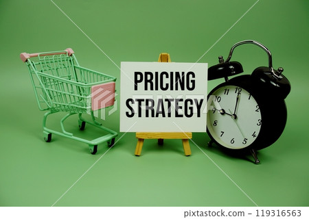 Pricing Strategy text message on paper card with alarm clcok and trolley shopping cart on green background Pricing Strategy text message on paper card with alarm clcok and trolley shopping cart on green background 119316563