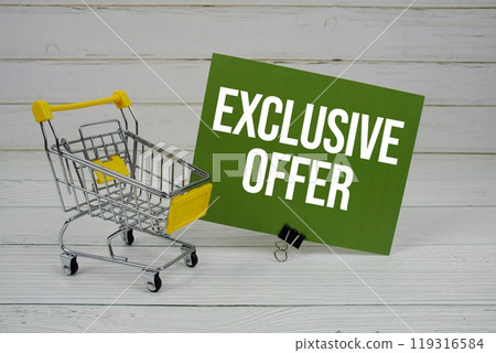 Exclusive Offer text message on paper card with mini trolley shopping cart on wooden background 119316584