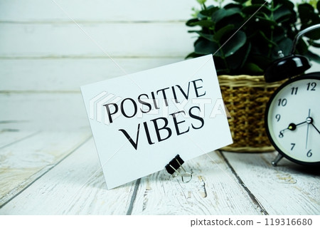 Inspirational quote Positive Vibes text message with alarm clock on wooden background 119316680