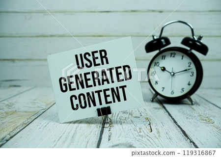 User Generated Content text on paper card with alarm clock on wooden background 119316867