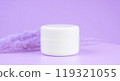 a white glass jar for moisturizing cream with a gold lid on purple or lilac background. Mockup for branding product packaging 119321055