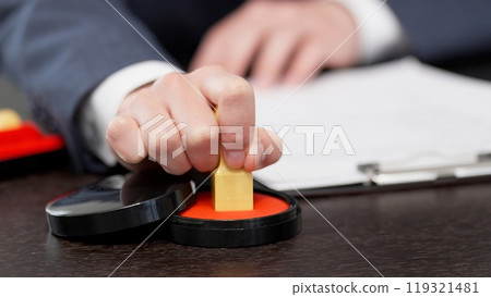 The hands of a businessman stamping a contract The hands of a businessman stamping a contract 119321481