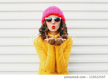 Fashion cool girl blowing red lips kiss, colorful knitted yellow sweater hat on white background 119322547