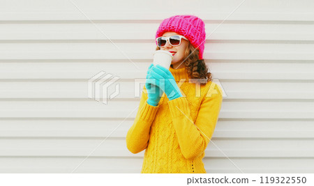 Fashion pretty young woman drinks coffee wearing knitted colorful pink hat yellow sweater 119322550