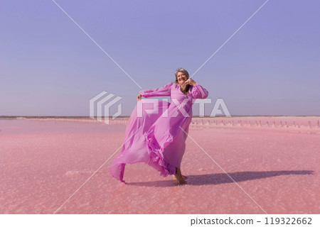 Pink Lake Woman Dress Photo Shoot - A woman wearing a pink dress poses on a pink salt lake. 119322662