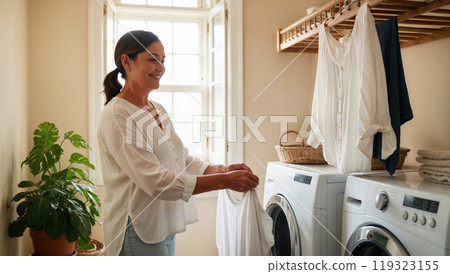Woman taking care of laundry chores putting clothes in washing machine at home Woman taking care of laundry chores putting clothes in washing machine at home 119323155