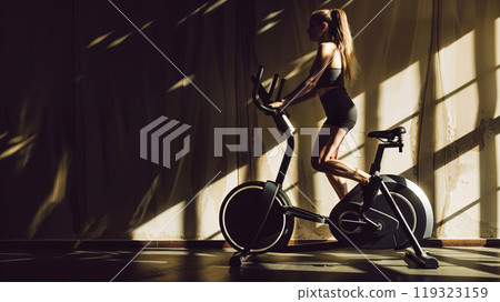 Young sporty woman working out using stationary bicycle in gym 119323159