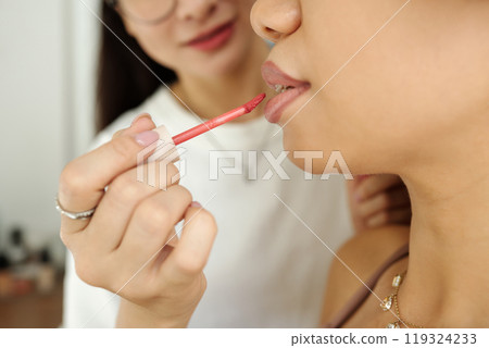 Artist Applying Lipstick On Lips Of Model Artist Applying Lipstick On Lips Of Model 119324233