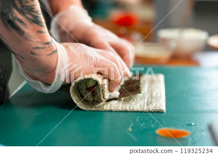 Preparing sushi rolls with fresh ingredients at a culinary studio Preparing sushi rolls with fresh ingredients at a culinary studio 119325234